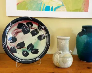 photo of ceramic plate and vase displayed on a shelf.